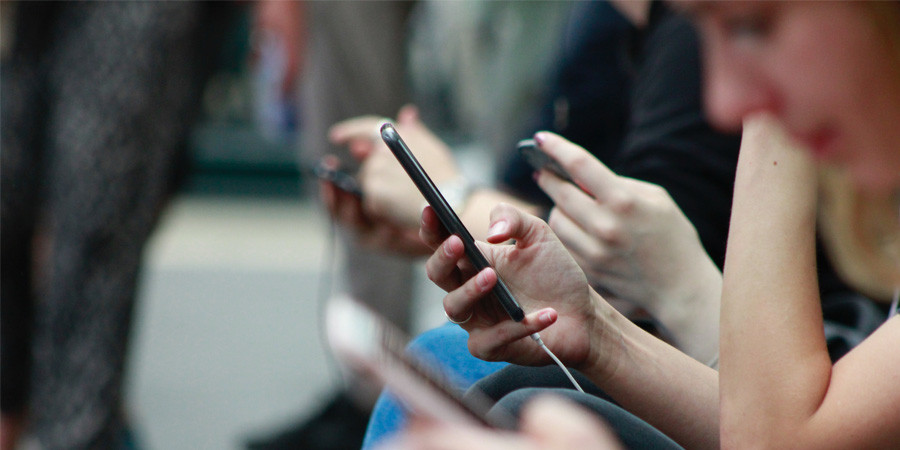 People scroll on mobile phones on the tube.